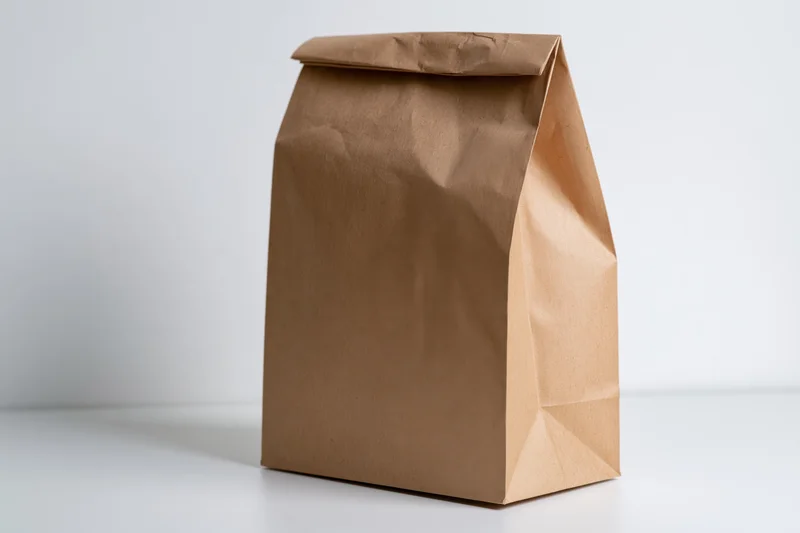Brown kraft paper bag standing upright on white surface