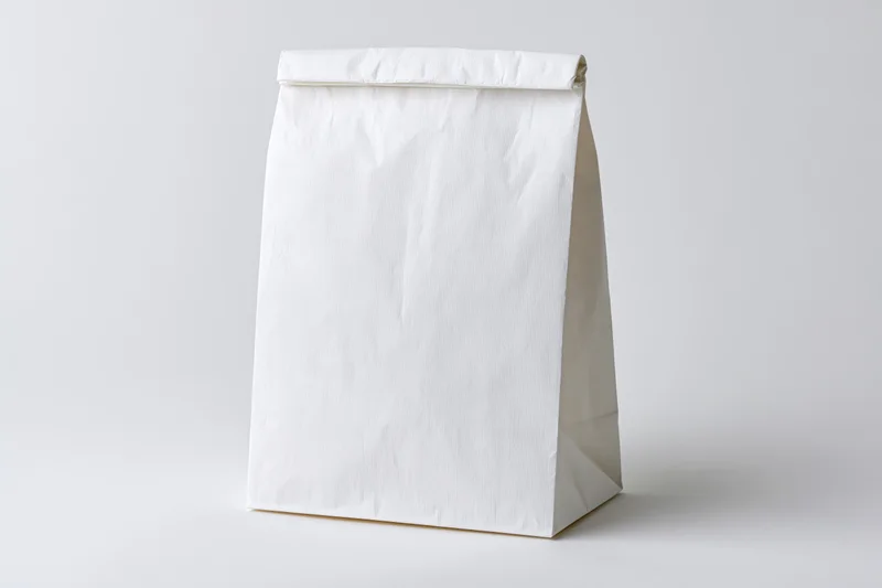 Plain white paper bag standing upright on a white surface