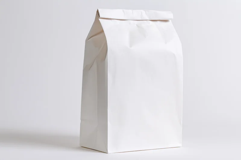 Plain white paper bag standing upright on a white surface