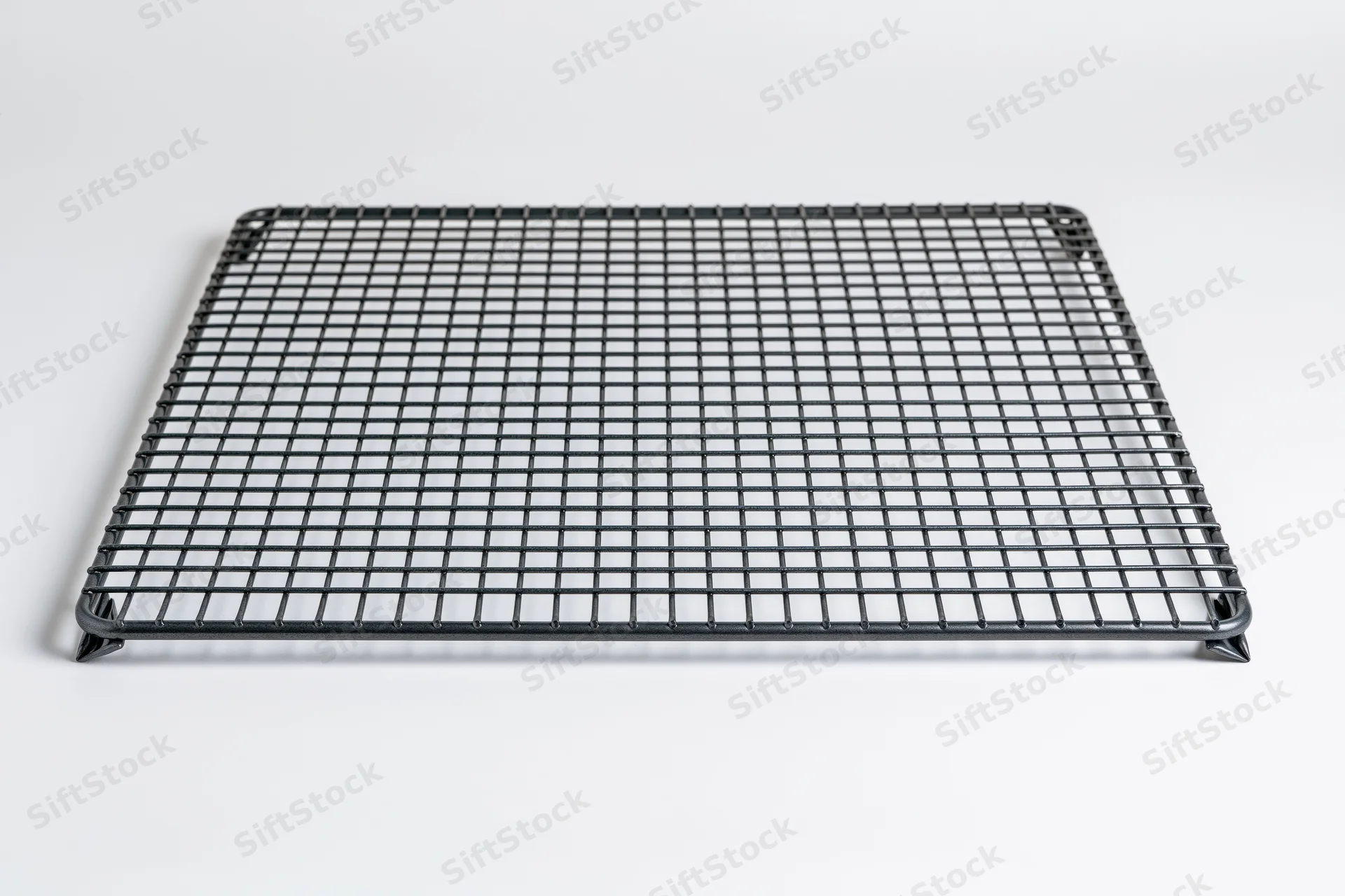 Rectangular dark metal wire cooling rack lying flat on white background