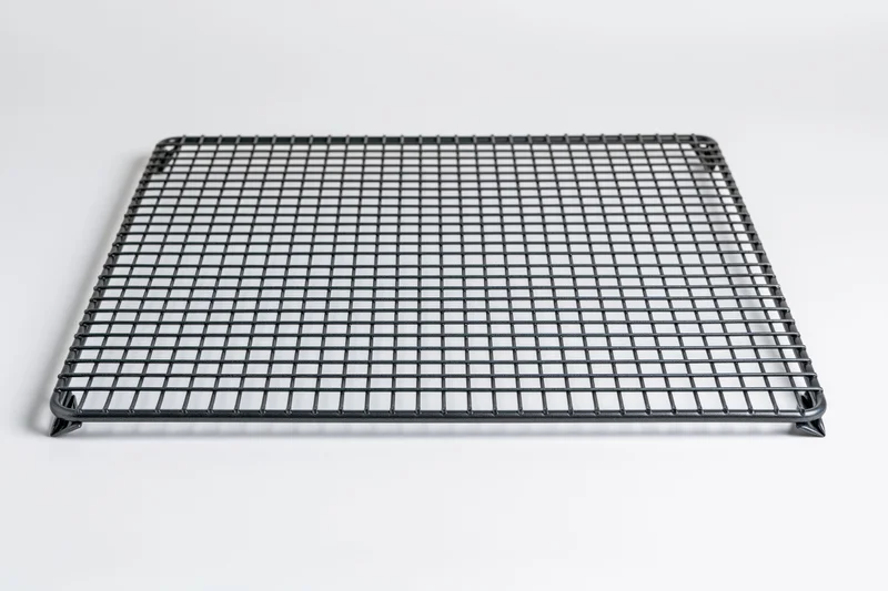 Rectangular dark metal wire cooling rack lying flat on white background