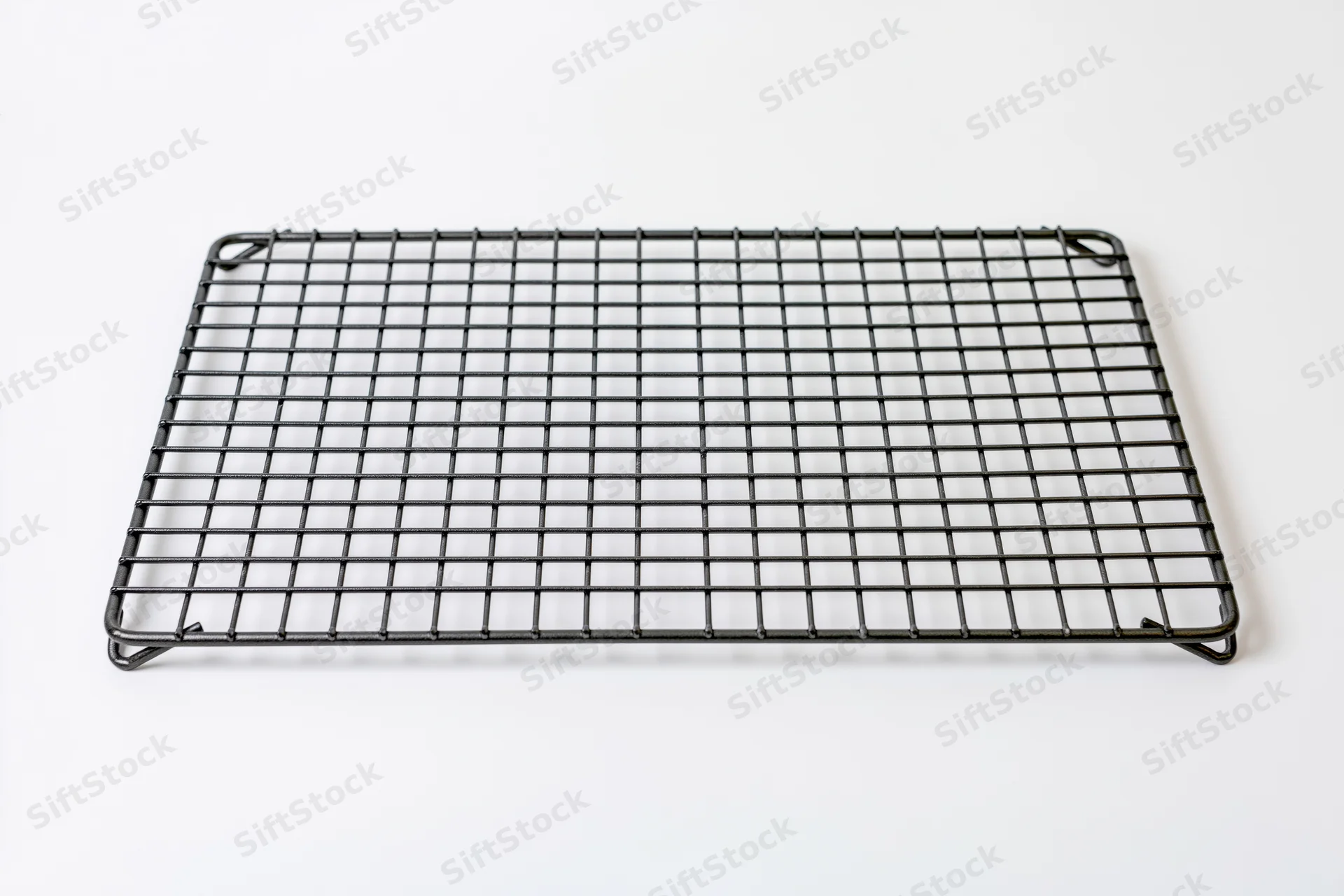 Rectangular dark metal wire cooling rack lying flat on white surface