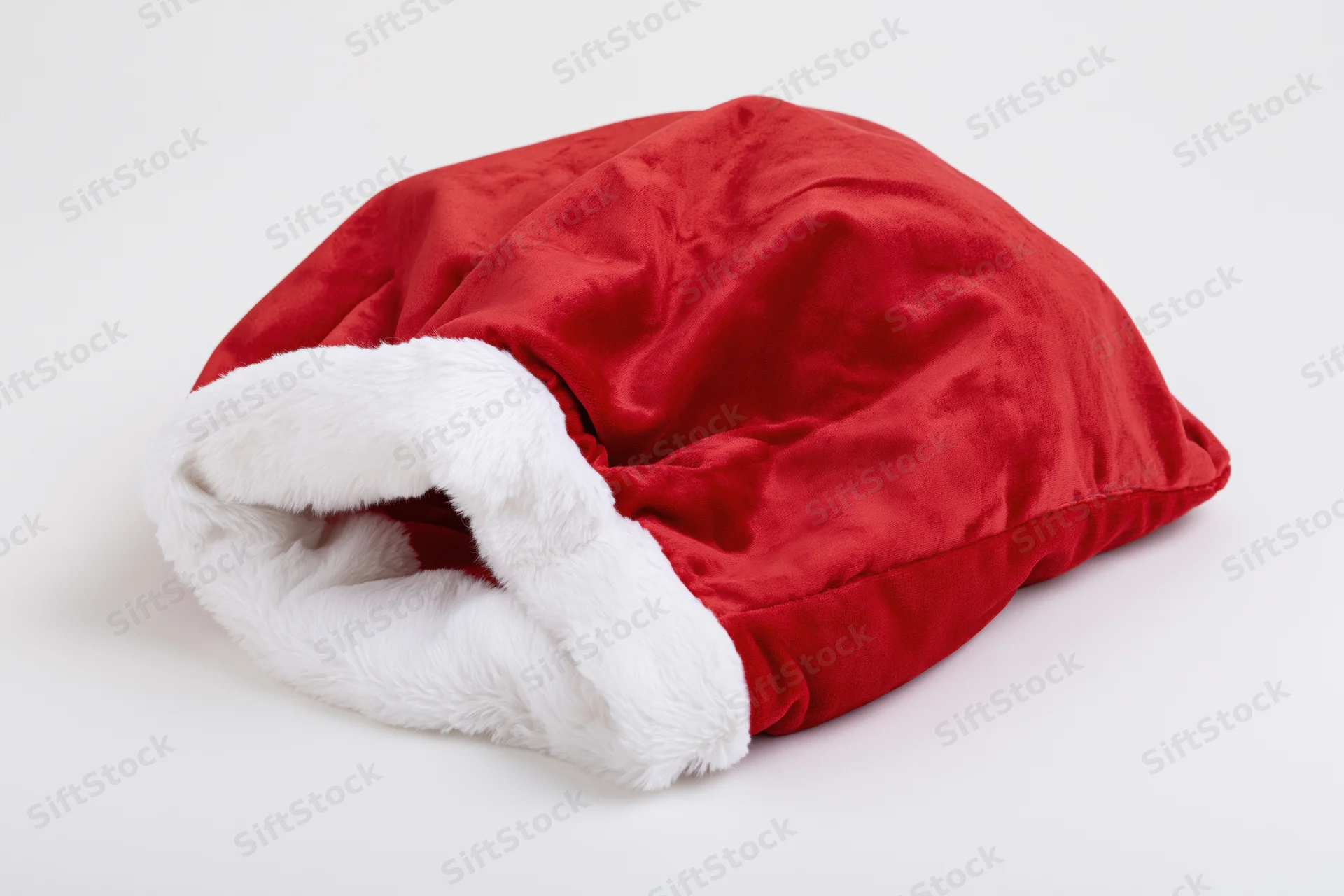 Red velvet santa gift sack lying flat and empty on white background