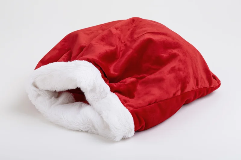Red velvet santa gift sack lying flat and empty on white background