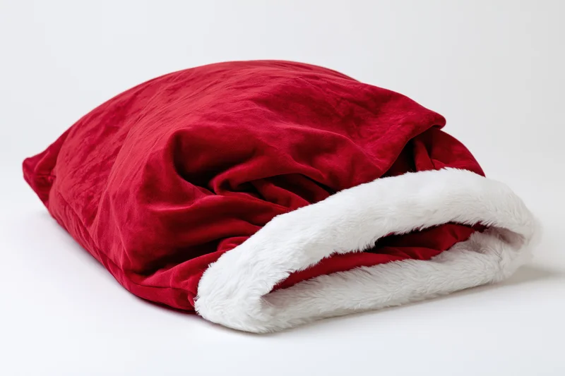 Red velvet santa gift sack lying flat and empty on white background