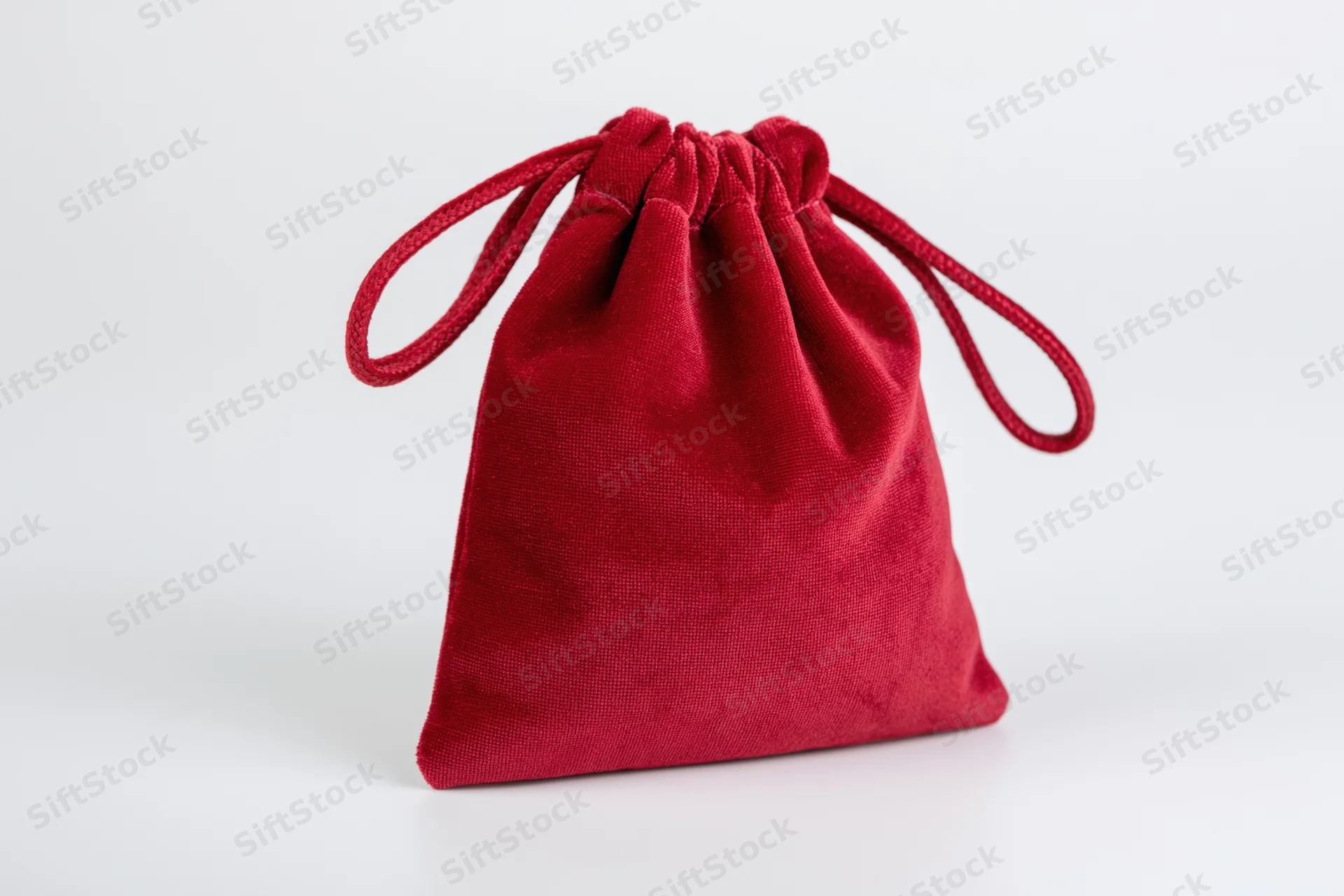 Red velvet drawstring pouch standing upright on white background