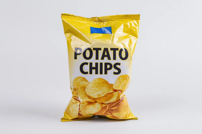 Sealed bag of potato chips standing upright on white background