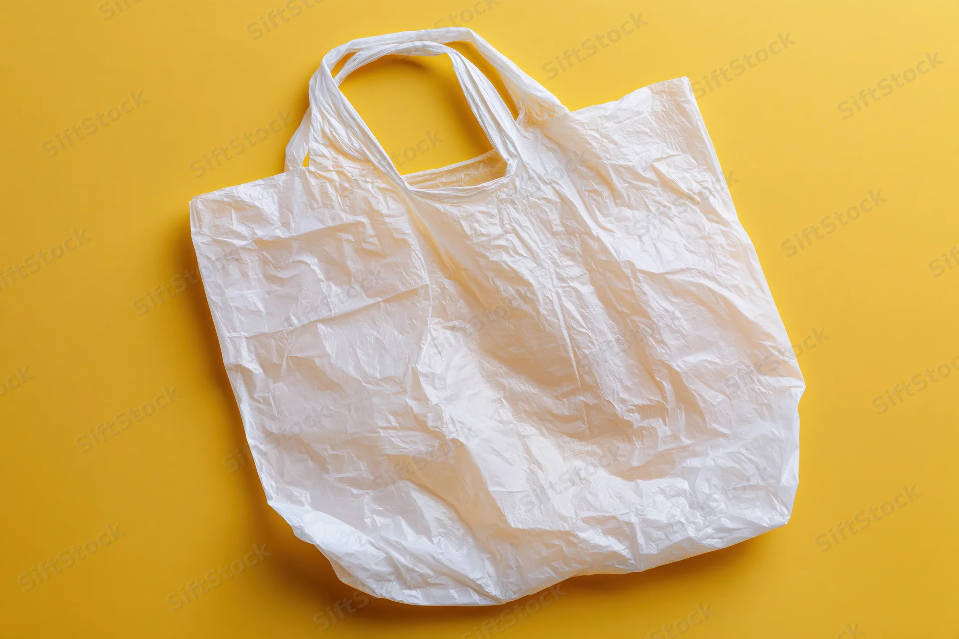Crumpled white plastic grocery bag on yellow background