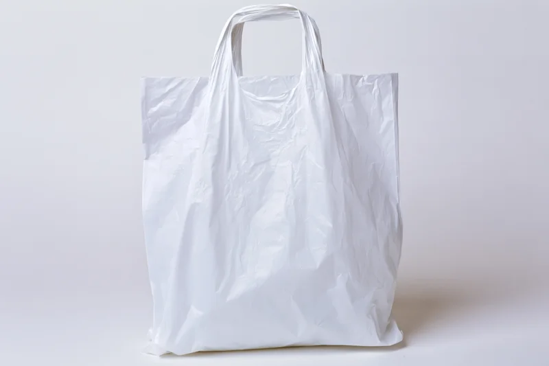 Empty white plastic shopping bag standing upright on plain white background