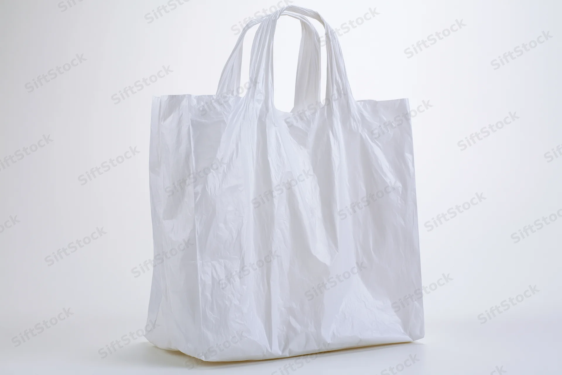 Empty white plastic shopping bag standing upright on a white surface