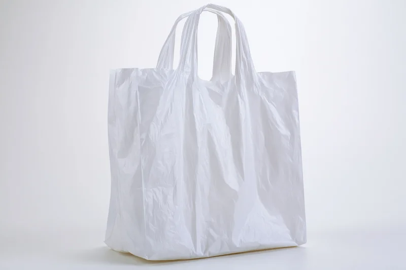 Empty white plastic shopping bag standing upright on a white surface