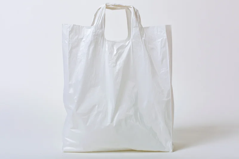 Empty white plastic shopping bag standing upright on plain white surface