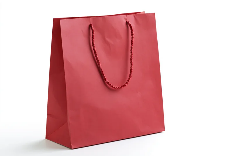 Red glossy paper shopping bag with twisted rope handles on white background