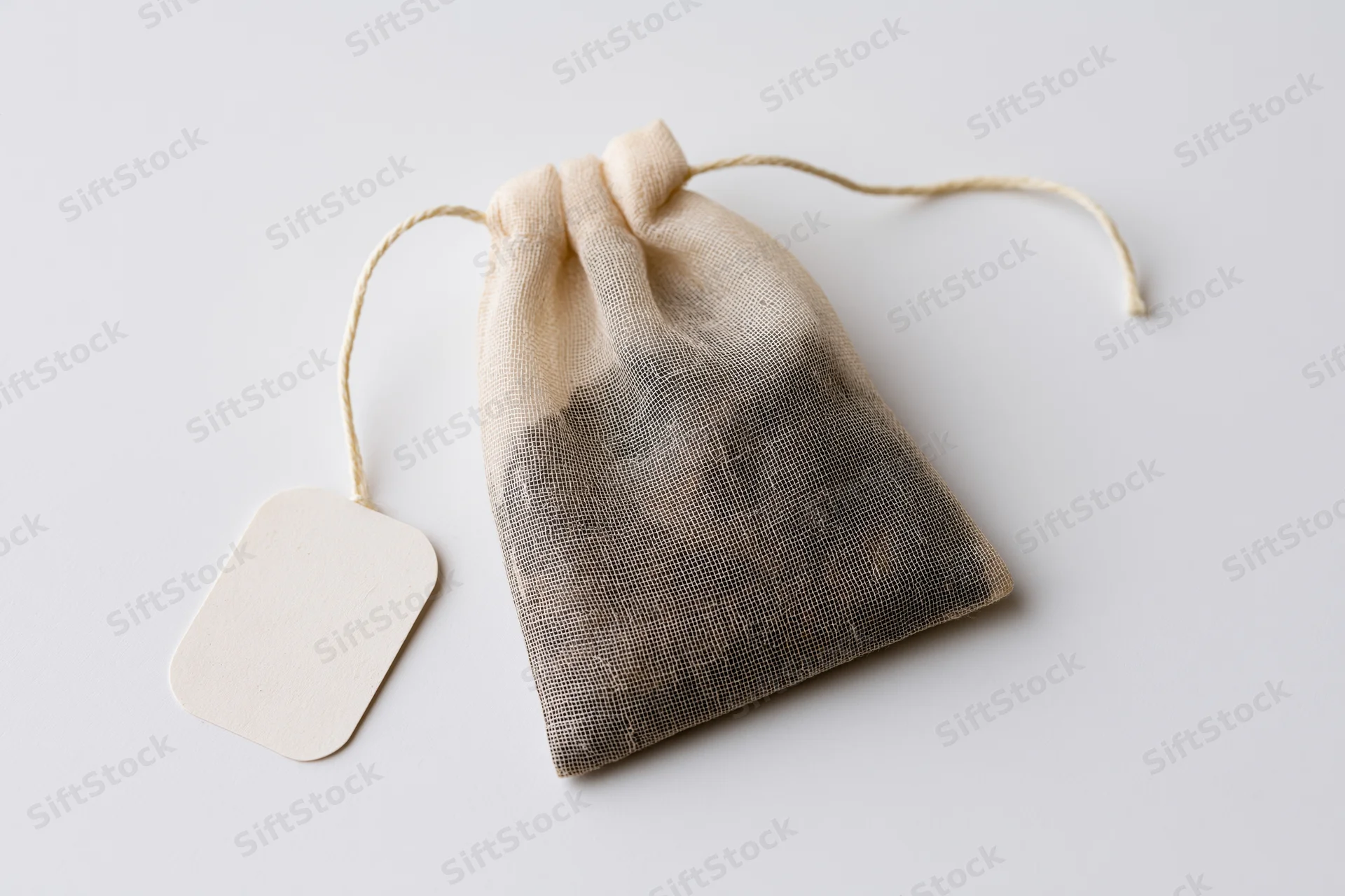 Single tea bag with drawstring and blank paper tag on white background