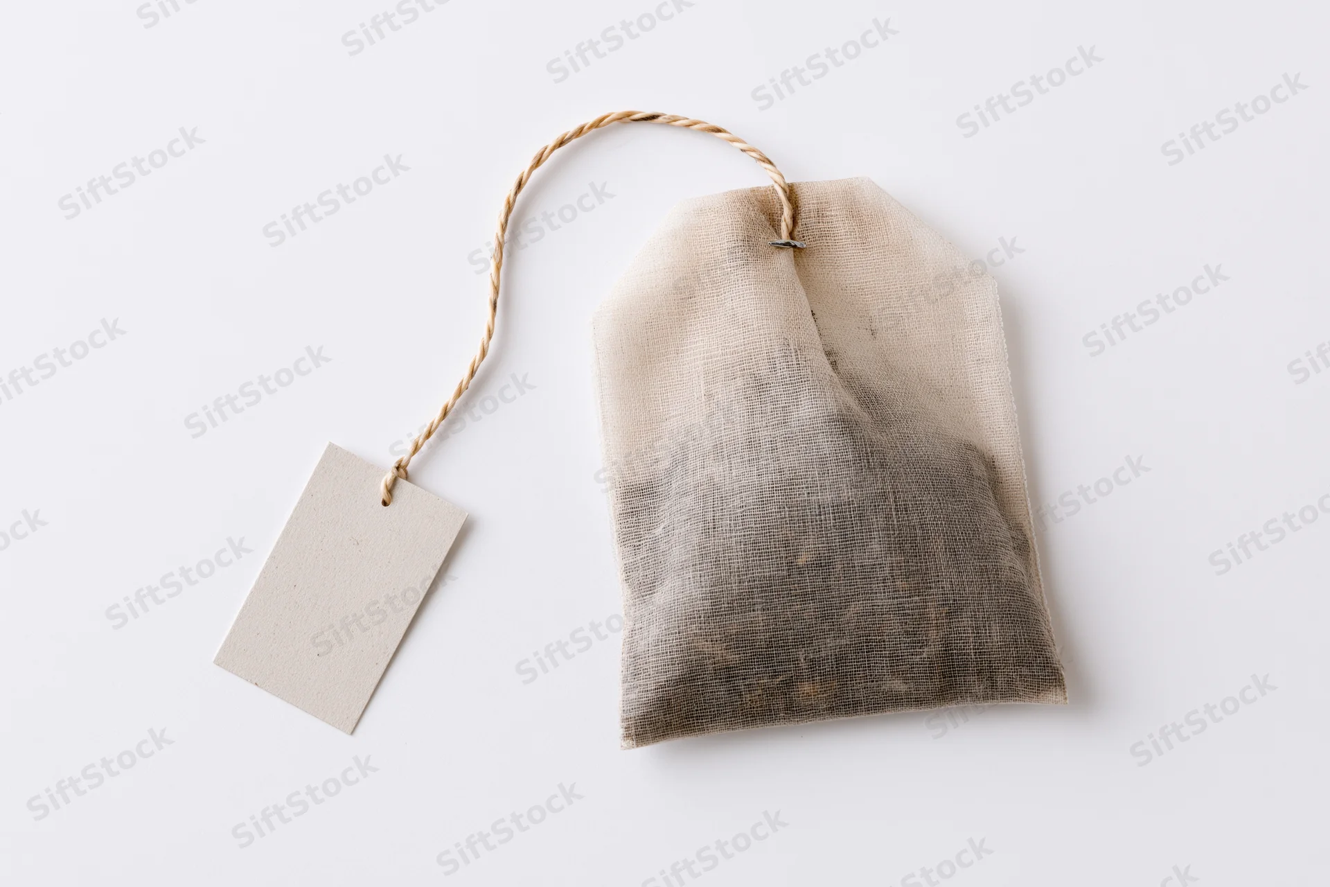 Unused tea bag with paper tag on white background