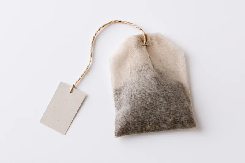 Unused tea bag with paper tag on white background