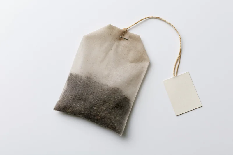 Unused tea bag with paper tag on white background