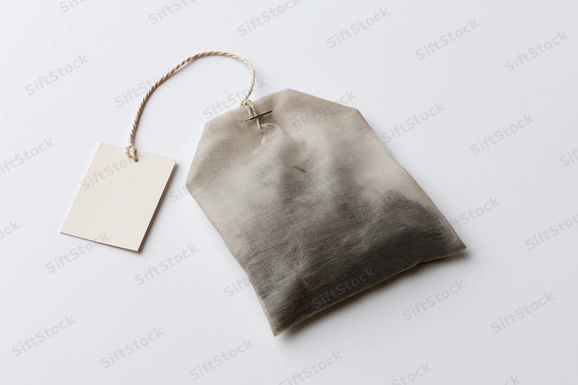 Single unused tea bag with attached paper tag on white background