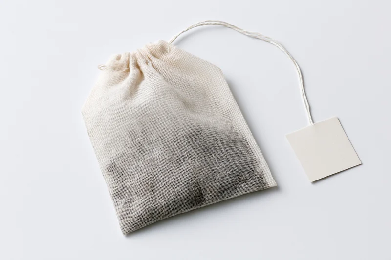 Single unused tea bag with square paper tag on white background
