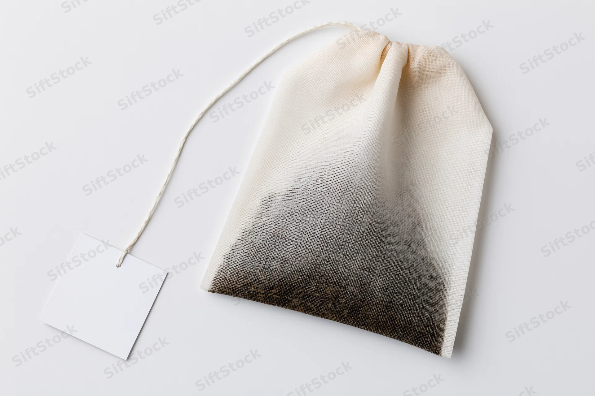 Unused tea bag with blank paper tag on white surface