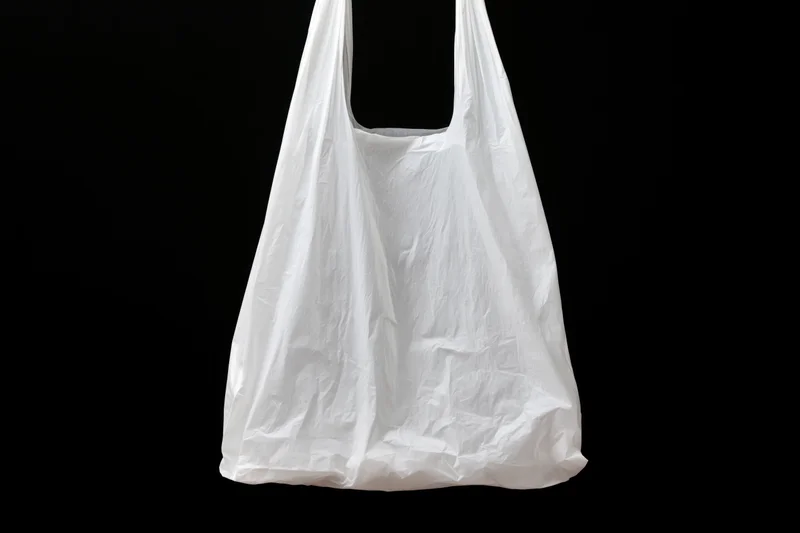 White plastic grocery bag hanging open against black background