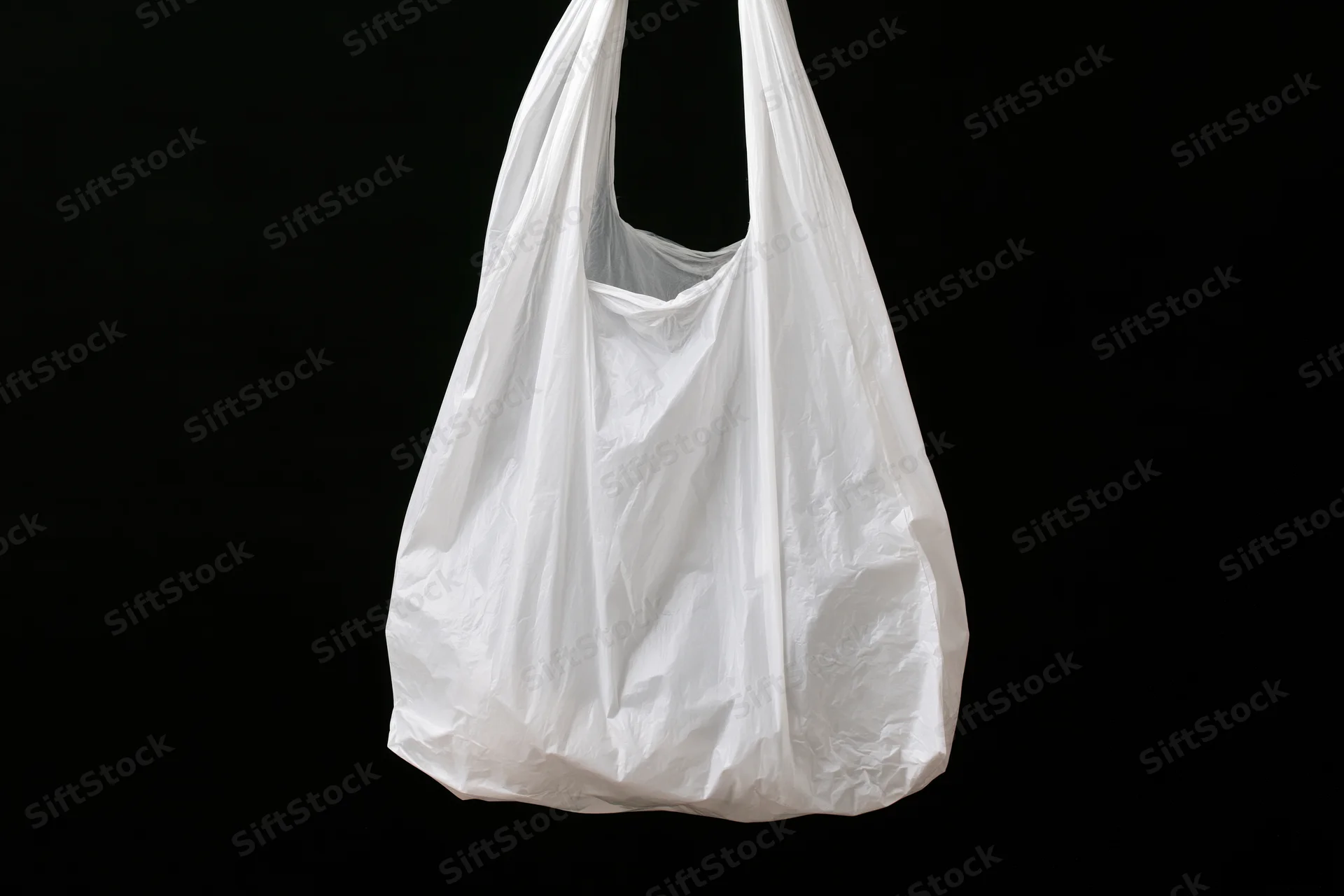 White plastic grocery bag hanging open against black background