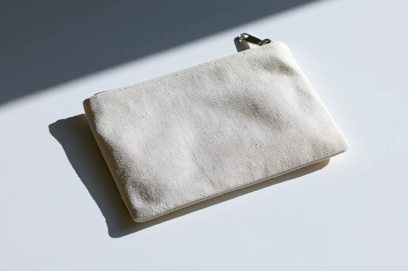 Small blank canvas zip pouch lying flat on white surface