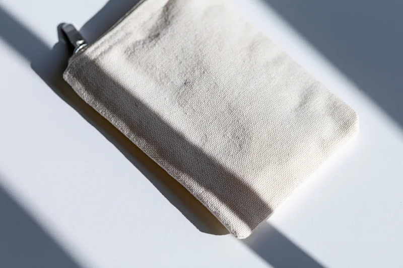 Small blank canvas zip pouch lying flat on white surface