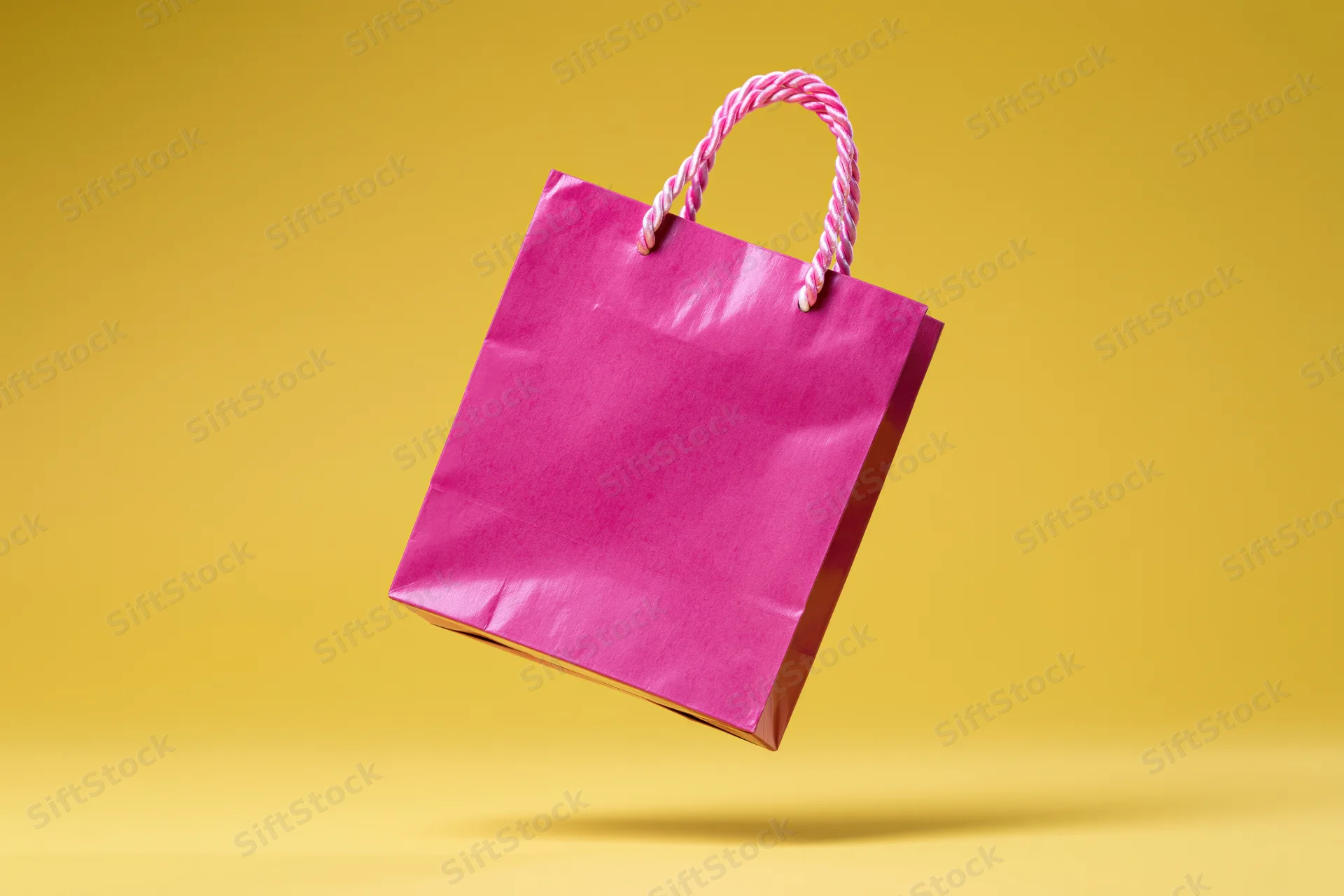 Pink paper shopping bag floating against yellow background