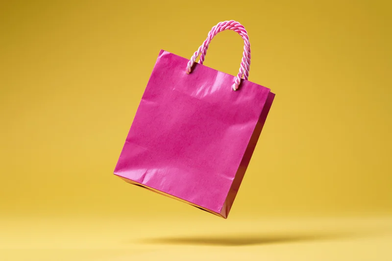 Pink paper shopping bag floating against yellow background