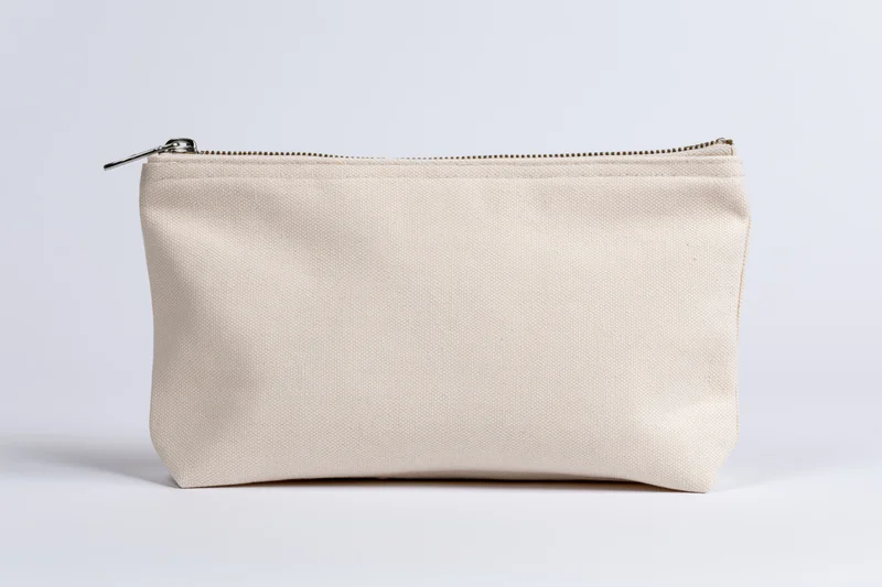 Small beige canvas pouch with zipper standing upright on white background