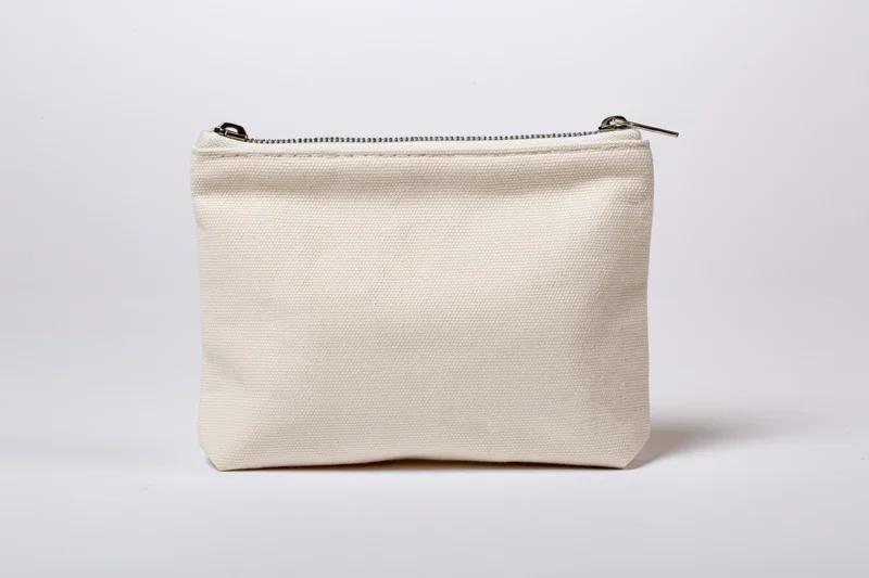 Small cream canvas pouch with zipper standing upright on white background