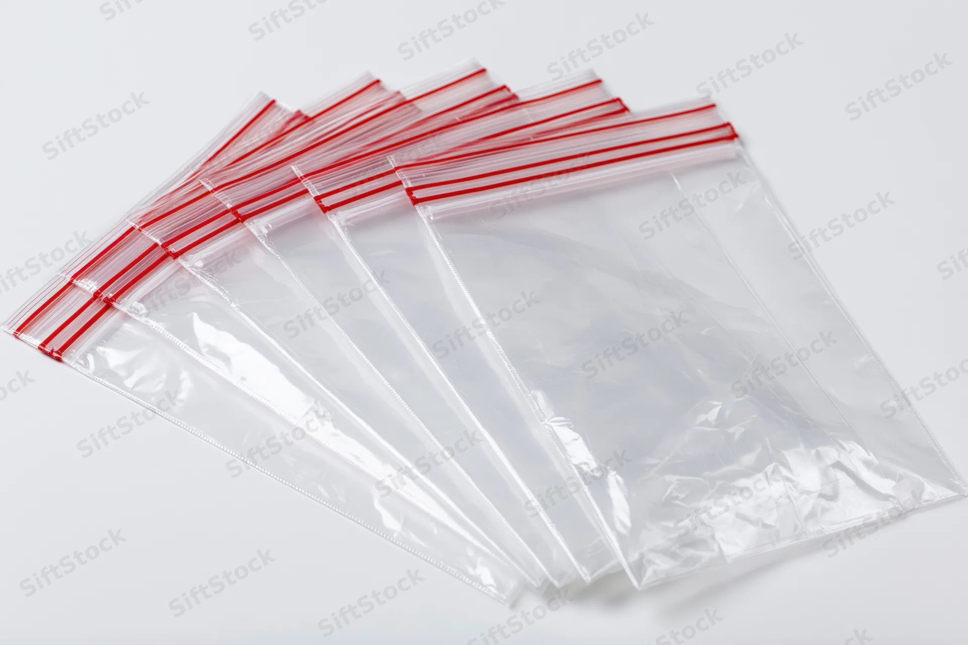 Stack of clear resealable zip-lock plastic bags fanned out on white background