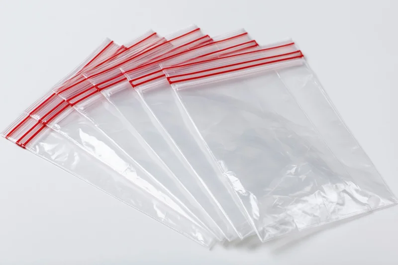 Stack of clear resealable zip-lock plastic bags fanned out on white background