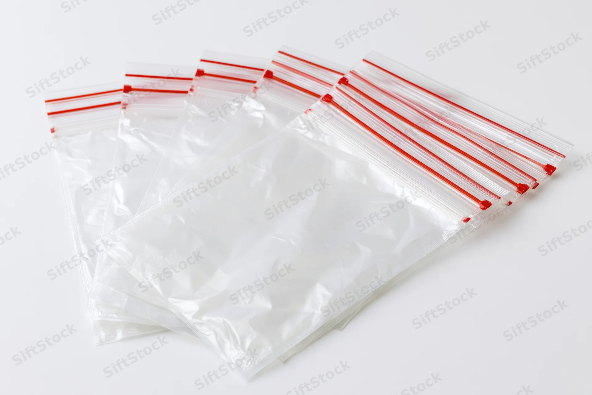 Clear resealable zip-lock plastic bags fanned out on white surface