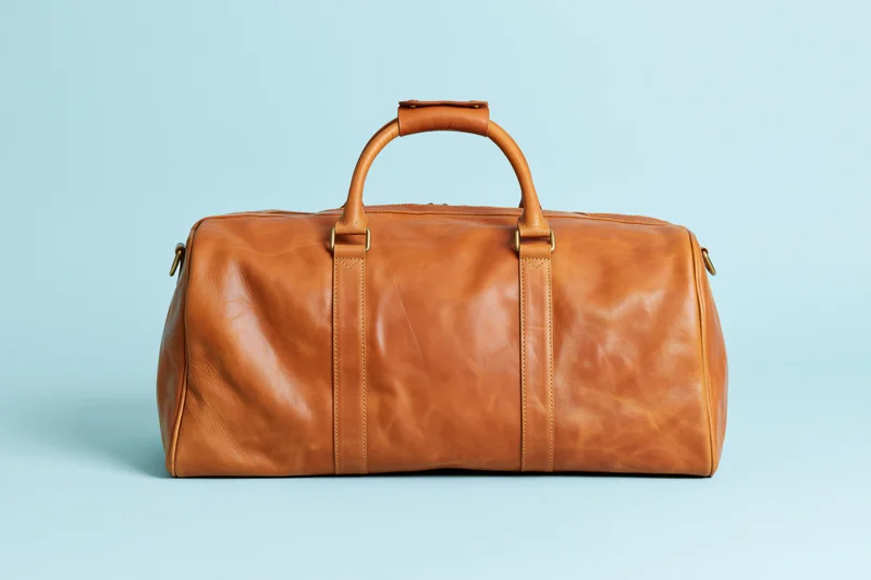 Tan leather duffle bag centered on a pale blue background