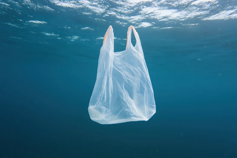 Translucent white plastic shopping bag floating suspended in deep blue ocean water