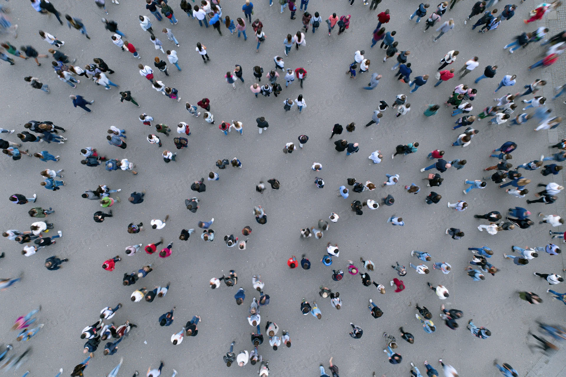 Aerial top-down view of a dense crowd of people walking across a city street