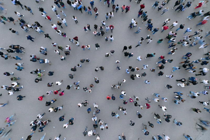 Aerial top-down view of a dense crowd of people walking across a city street