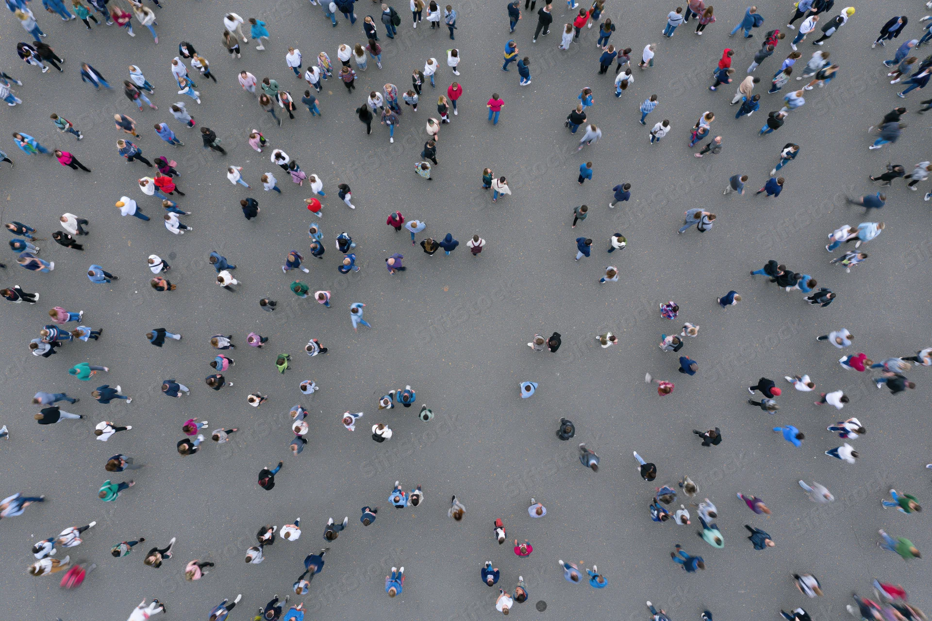 Aerial top-down view of a dense crowd of people walking across a city pavement