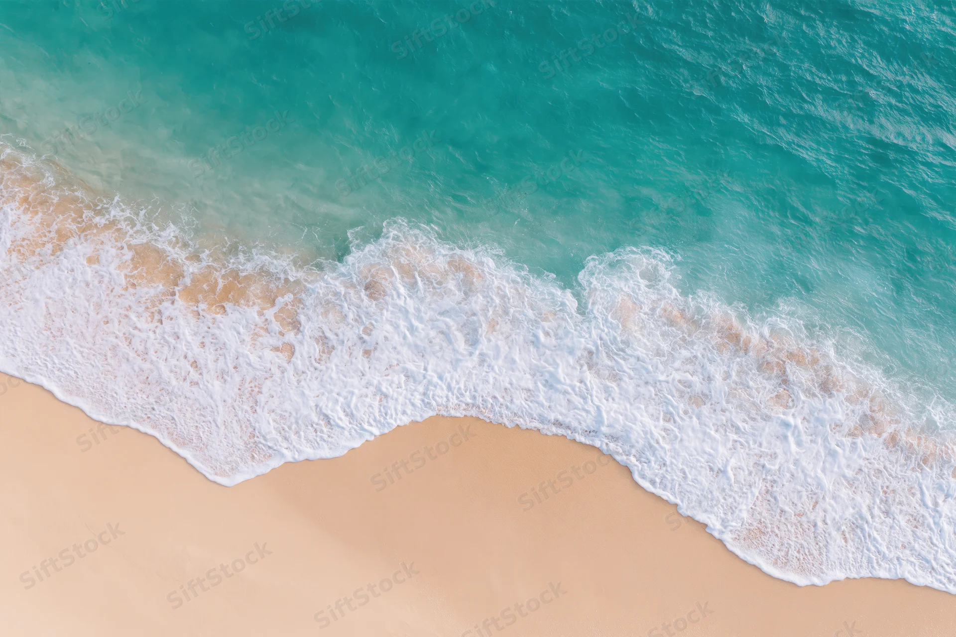 Aerial top-down view of gentle ocean wave washing onto sandy beach