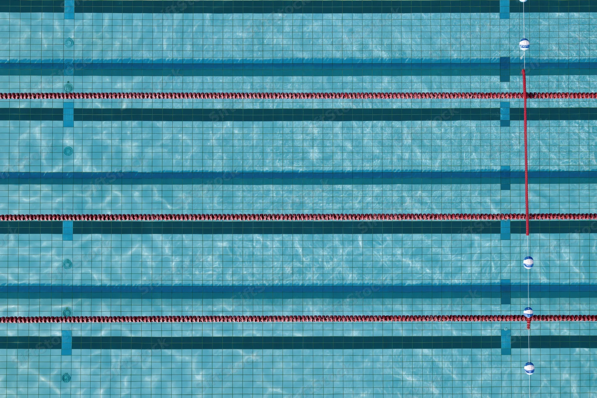 Aerial top-down view of empty olympic swimming pool lanes with red dividers and blue tiles