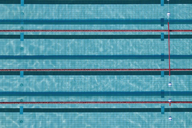 Aerial top-down view of empty olympic swimming pool lanes with red dividers and blue tiles