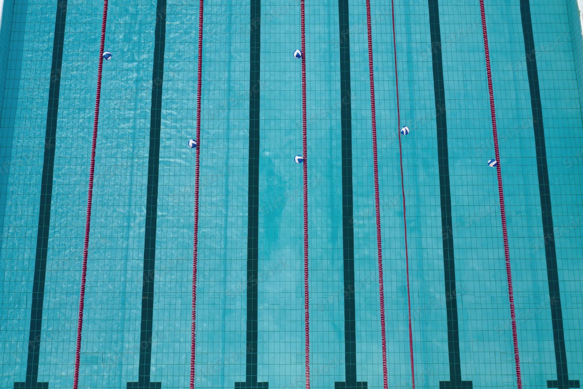 Aerial top-down view of an empty olympic competition swimming pool with lane dividers and tiled surface