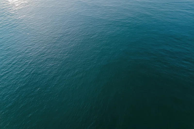 Aerial top-down view of calm open water surface with sunlight reflection