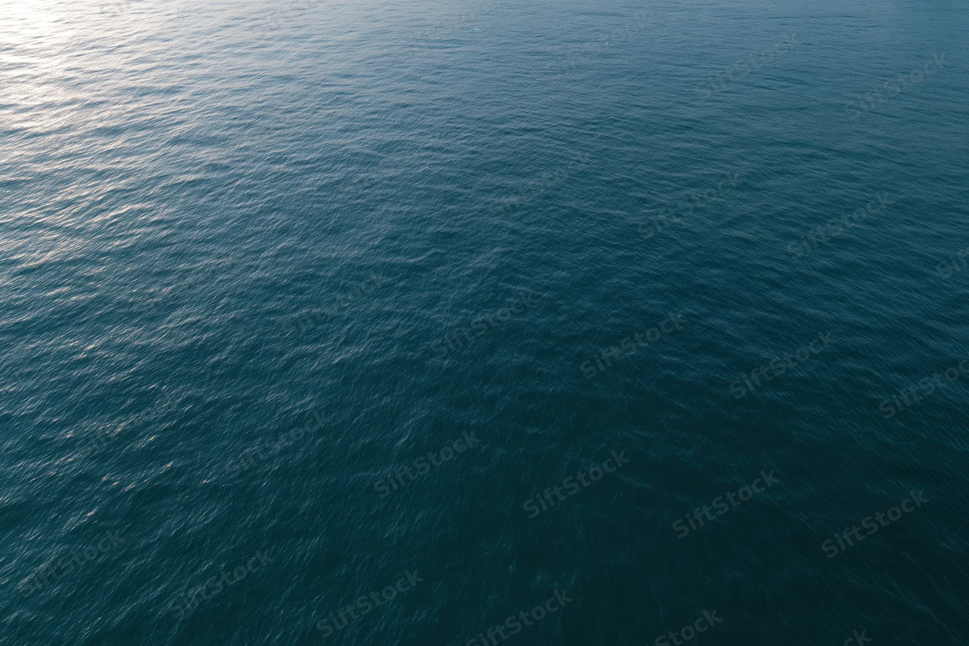 Aerial top-down view of calm ocean surface with gentle ripples and light reflection