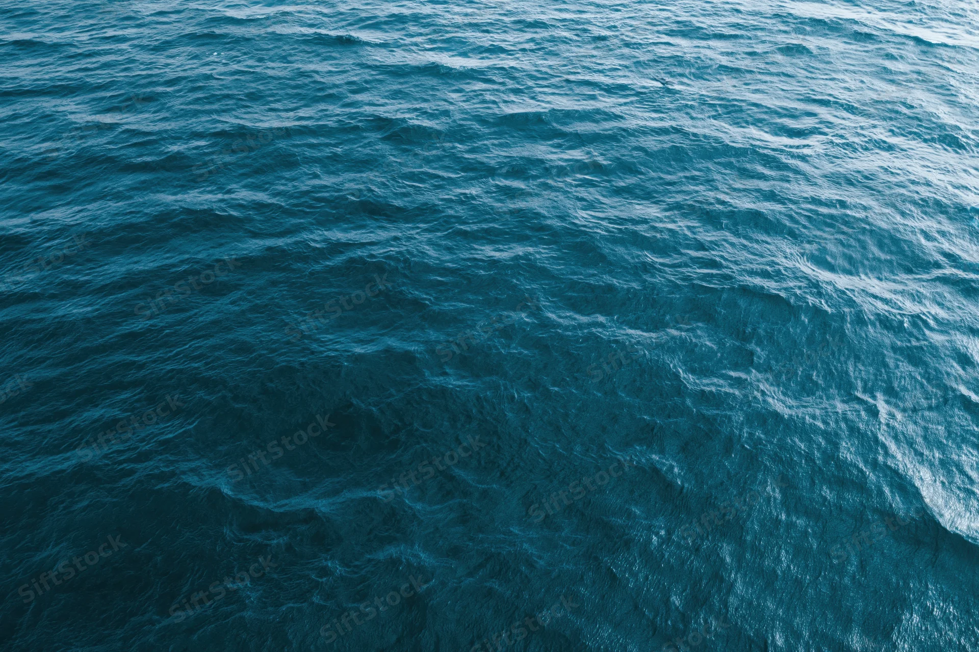 Aerial top-down view of open ocean surface with small ripples and blue water texture
