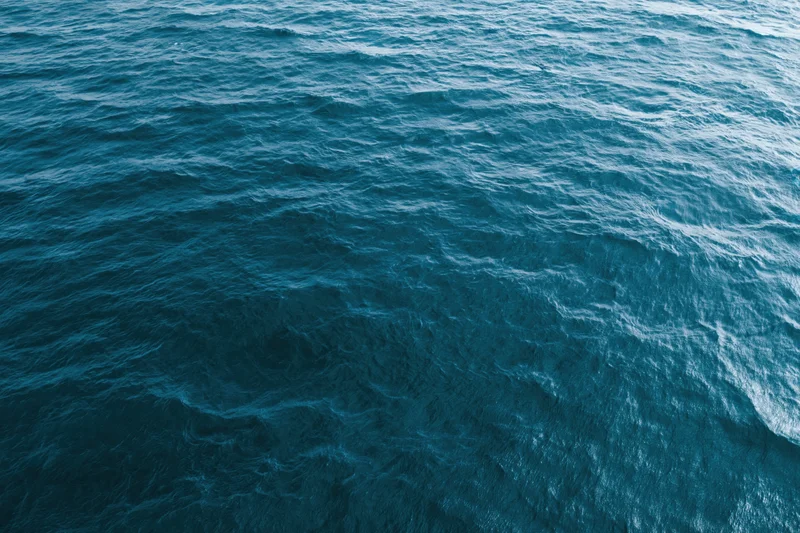 Aerial top-down view of open ocean surface with small ripples and blue water texture