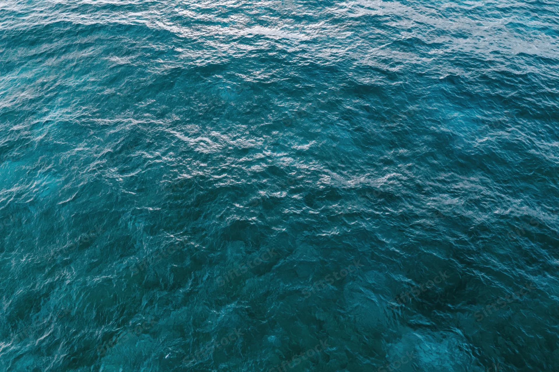 Aerial top-down view of open ocean surface with small ripples and light reflections