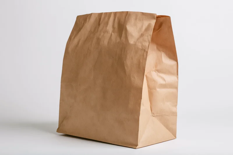 Brown kraft paper bag standing upright open on white background